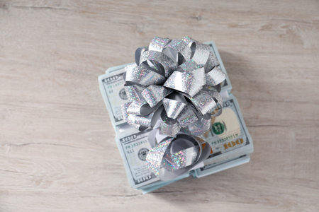 Dollar banknotes with bow on light wooden background, top viewの写真素材