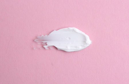 Sample of moisturizing cream on pink background, top view