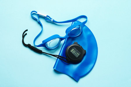 Goggles, digital stopwatch and swim cap on light blue background, flat layの写真素材