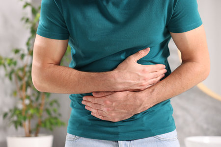 Man suffering from stomach ache and nausea in bathroom, closeup