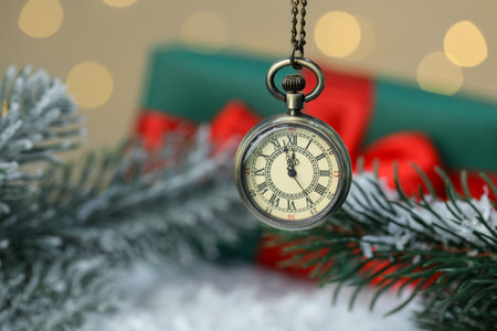 Pocket watch, fir branches, gift box and artificial snow against golden background with blurred lights, closeup. New Year greeting cardの写真素材