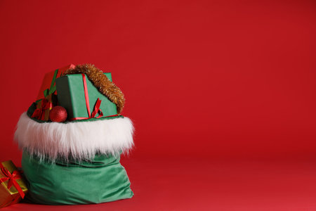 Santa Claus bag with Christmas gifts, tinsel and baubles on red background. Space for textの写真素材