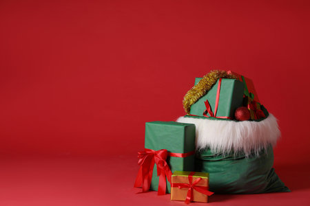 Santa Claus bag with Christmas gifts, tinsel and baubles on red background. Space for textの写真素材