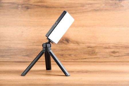 LED lamp on tripod against wooden background. Space for textの写真素材