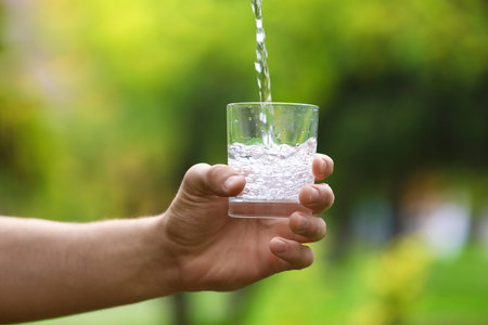 Man splashing water in glass on blurred green background, closeupの写真素材