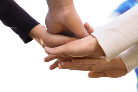 Group of volunteers stacking hands outdoors, closeup