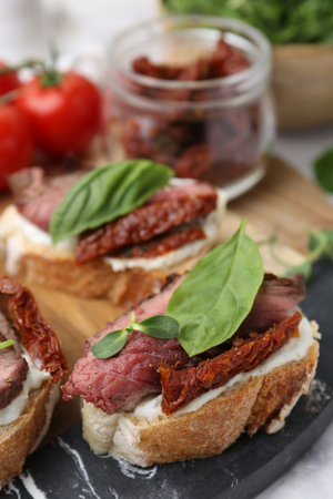 Bruschettas with roast beef, cream cheese, basil, sun-dried tomatoes and fresh vegetables on table, closeupの写真素材