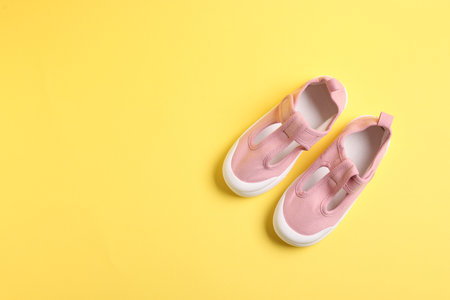 Pair of stylish kid's shoes on yellow background, flat lay. Space for textの写真素材