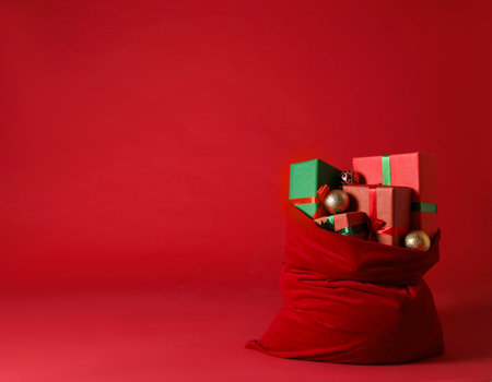 Santa Claus bag with Christmas gifts and baubles on red background. Space for textの写真素材