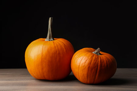 Two pumpkins for Halloween on wooden table against black background, closeupの写真素材