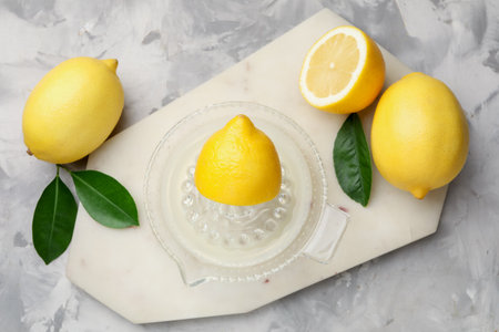 Lemon juice in juicer, leaves and fresh lemons on light gray table, flat layの写真素材