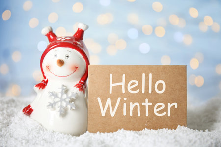 Hello winter card with snowman figure in snow and bokeh lightsの写真素材
