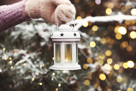 Merry Christmas and Happy Holidays. Greeting card with woman holding lantern outdoors