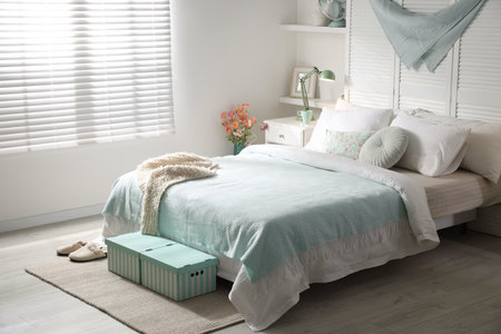 Stylish bedroom with large bed, pillows and lamp. Interior design