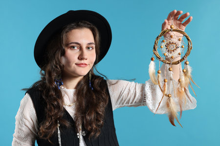 Woman with beautiful dream catcher on light blue background