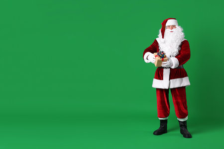 Santa Claus with Christmas gift on green backgroundの写真素材