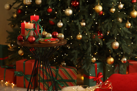 Burning candles and festive decor on table near Christmas tree indoorsの写真素材