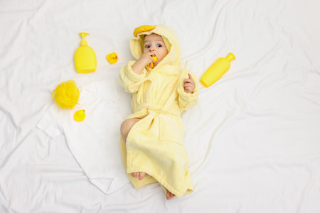 Cute baby in bathrobe and bathroom accessories on bed, top viewの写真素材
