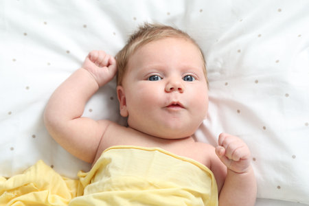 Cute newborn baby in bed at home, top viewの写真素材
