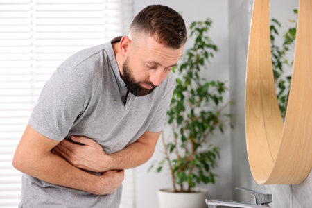 Man suffering from stomach ache and nausea in bathroomの写真素材