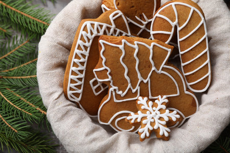 Tasty gingerbread cookies in basket and fir tree branches on table, top view. Christmas treat