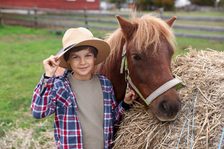 Equine assisted therapy. Boy with beautiful pony near stack of hay outdoors. Lovely domesticated petの写真素材