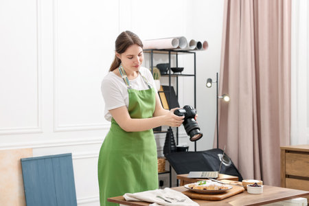 Woman taking picture of croissants at table in studio. Professional food photographyの写真素材