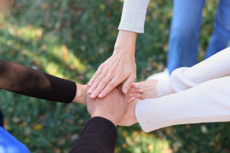 Group of volunteers stacking hands outdoors, closeupの写真素材