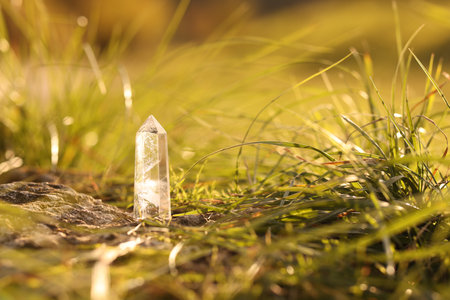 Aura. Beautiful healing crystal on green grass outdoors, closeup. Space for textの写真素材