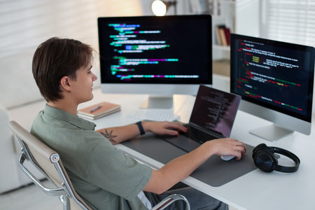Programmer working on computer and laptop at white table in officeの写真素材