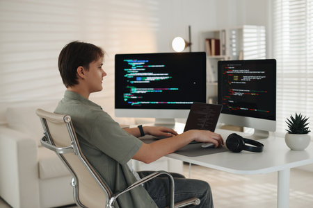 Programmer working on computer and laptop at white table in officeの写真素材
