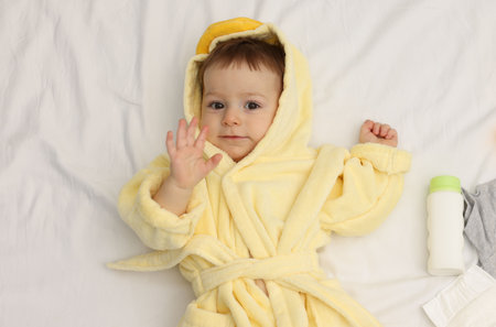 Cute baby in bathrobe and bathroom accessories on bed, top viewの写真素材