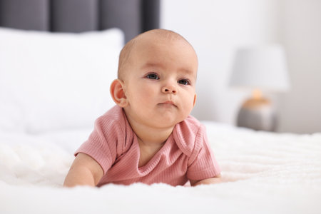 Portrait of cute little baby on bed at home