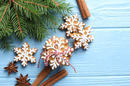 Tasty gingerbread cookies, spices and fir tree branches on light blue wooden background, flat lay. Christmas treatの写真素材