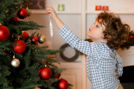 Little boy decorating Christmas tree at homeの写真素材