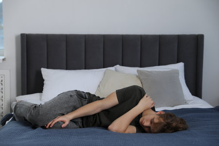 Depressed teenage boy on bed at home