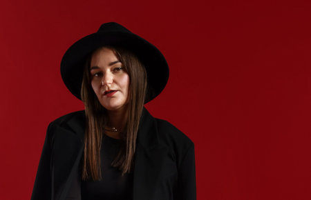 Beautiful young woman in stylish clothes posing on red background, space for textの写真素材