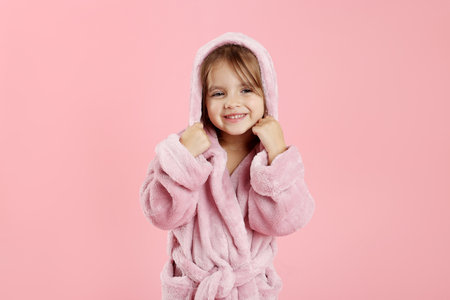 Cute girl in bathrobe on pink backgroundの写真素材