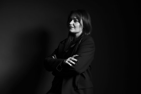 Beautiful young woman in stylish clothes on dark background. Black and white effectの写真素材