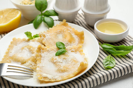 Delicious ravioli with cream sauce and basil served on white table, closeupの写真素材