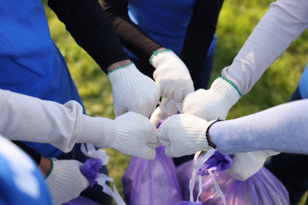 Group of volunteers bumping fists outdoors, closeupの写真素材