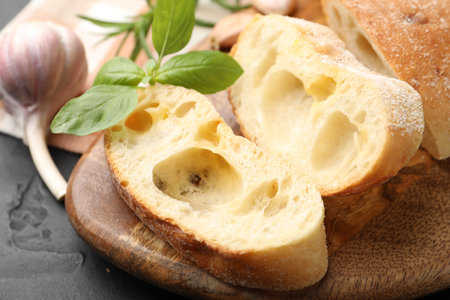 Fresh cut ciabatta, garlic and basil on dark textured table, closeupの写真素材