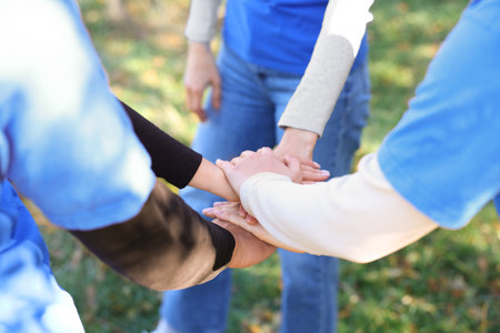 Group of volunteers stacking hands outdoors, closeup