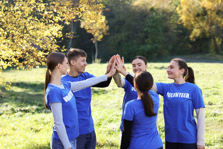 Group of happy volunteers joining hands in park