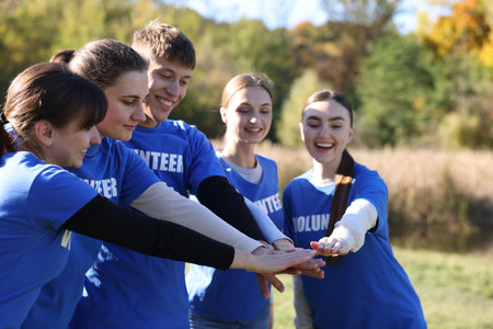 Group of happy volunteers stacking hands in parkの写真素材