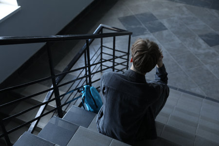 Depressed teenage boy and backpack on stairs indoors, above viewの写真素材