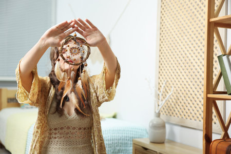 Woman with beautiful dream catcher in bedroom, selective focus. Space for textの写真素材