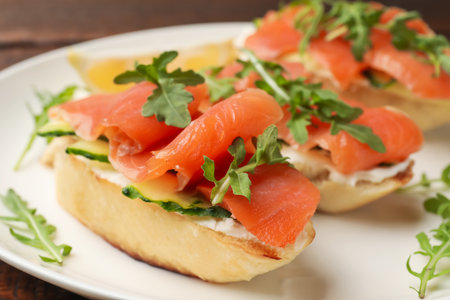 Tasty bruschettas with salmon, cream cheese, cucumber and arugula on plate, closeupの写真素材
