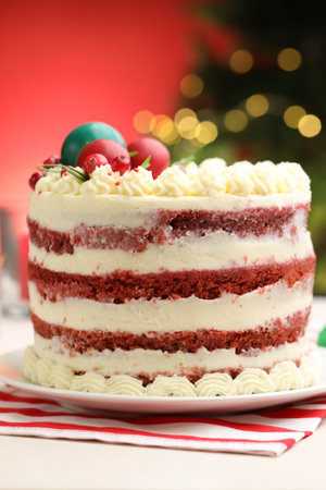Delicious sponge cake with Christmas decor on white table against red background with blurred lights, closeup. Bokeh effectの写真素材