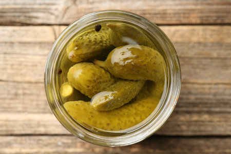 Pickled cucumbers in jar on wooden table, top viewの写真素材